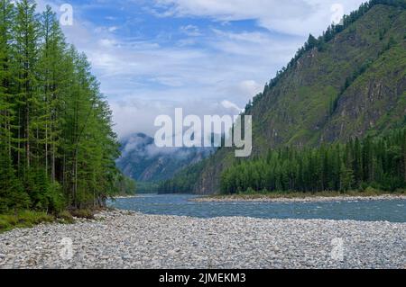 Niedrige Wolken in einer Bergschlucht über dem Fluss. Stockfoto