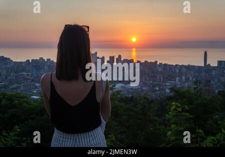 Batumi, Georgia, Blick von oben bei Sonnenuntergang. Junge, nicht erkennbare Frau, die von der Aussichtsplattform aus die Stadt Batumi überblickt Stockfoto