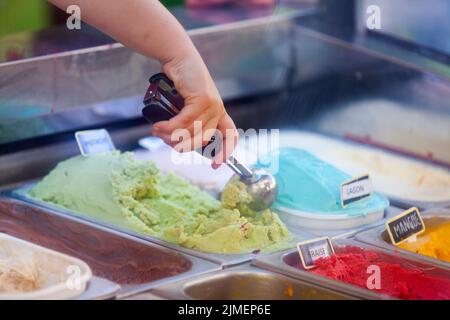 Nahaufnahme eines jungen Wamans, der im Eiscafé ein Eis schaufelt. Stockfoto