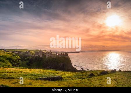 Sonnenuntergang auf den Ruinen von Dunluce Castle, auf den Klippen in Nordirland Stockfoto