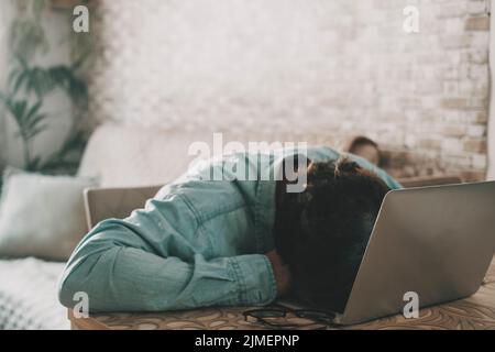 Überarbeiteter Freiberufler auf der Laptop-Tastatur. Ein Mann schlief nach der Arbeit auf dem Computer. Konzept von Stress und zu Hause hohe Rechnungen. Verzweiflung und Stockfoto