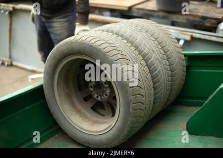 Räder des Autos. Austausch von Winterreifen beim Transport. Alte Reifen werden im Anhänger gestapelt. Reifenservice in der Stadt. Stockfoto