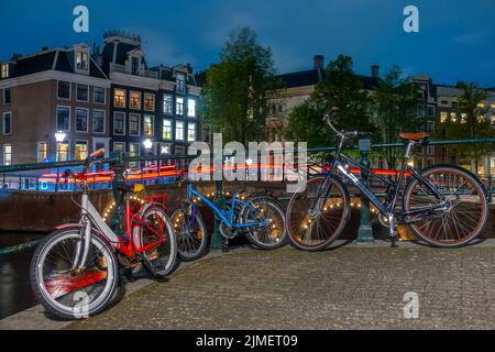 Fahrräder auf dem Canal Embankment in Amsterdam bei Nacht Stockfoto