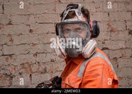 Baumeister trägt Vollmaske und Gehörschutz für Arbeiten in staubigen und lauten Umgebungen. Stockfoto