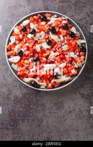 Katalanischer Kabeljau-Salat, auch bekannt als esqueixada, mit Kabeljau, Tomatenzwiebeln und Oliven-Nahaufnahme auf einem Teller auf dem Tisch. Vertikale Draufsicht von oben Stockfoto