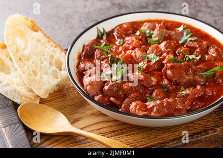 Moelas Guisadas schmorte langsam Hühnermagen in Tomatensauce in einer Schüssel auf einem Holztablett auf dem Tisch. Horizontal Stockfoto