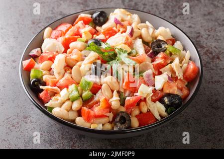 Spanische Empedrat weißen Bohnen Salat mit Kabeljau, Tomaten, Paprika, Zwiebeln, Eiern und schwarzen Oliven in einer Schüssel auf dem Tisch. Horizontal Stockfoto