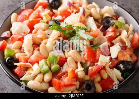 Mediterraner hausgemachter Kabeljausalat mit weißen Bohnen, Eiern und Gemüse in einer Schüssel auf dem Tisch. Horizontal Stockfoto