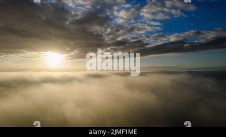 Luftaufnahme. Fliegen Sie im Nebel über den frühen Morgenwolken in der aufgehenden Sonne. Luftkamera aufgenommen. Flug über dem Kl Stockfoto