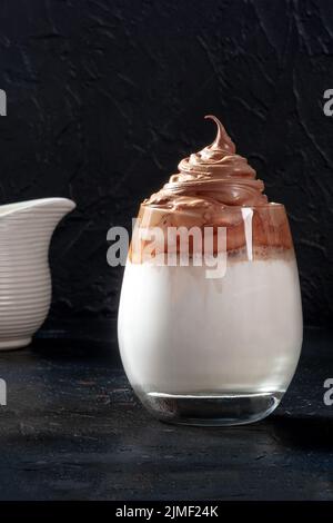 Dalgona kalter Kaffee in einem Glas auf schwarzem Hintergrund mit Kopierraum Stockfoto