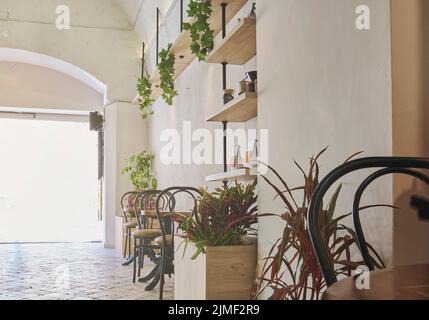 Moderne Bar-Café-Einrichtung mit Holztischen und -Stühlen in der Nähe von weißen Backsteinwänden. Original Deckenleuchten. Stockfoto