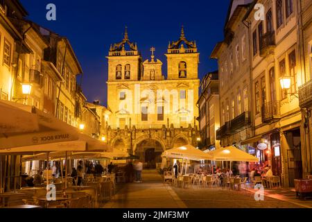 Braga, PORTUGAL - 25. Juni 2022: Menschen in Restaurants vor der Kathedrale von Braga zur blauen Stunde. Stockfoto