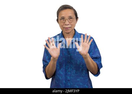 Asiatische ältere Frau, die auf dem Hintergrund mit winkenden Händen steht. Stockfoto