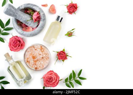 Flaches Design von Rosenkosmetik Konzept aus Mörtel und Stößel mit Rosenknospen mit Tropfersalz und Ölflasche auf weißem Hintergrund Stockfoto