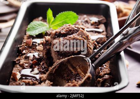 Schokoladeneis in Metallschale mit Minzblatt und Mandelnüssen Stockfoto