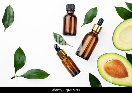 Tropfflaschen mit frischer reifer Avocado und ätherischem Öl auf weißem Tisch flach legen Stockfoto