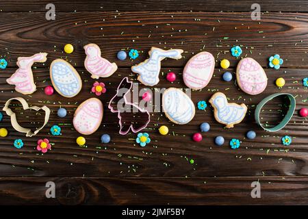 Zuckerstreuseln, Süßigkeiten, Ausstechformen, Ostergartuschen in Form von Hühnchen und Kaninchen auf Holztisch-Hintergrund. Stockfoto