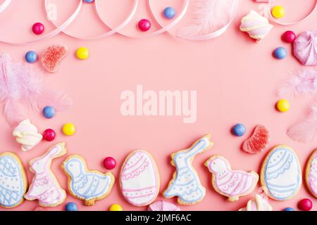 Bonbons und Osterklätzchen in Form von Hühnchen und Kaninchen auf rosa Hintergrund. Flaches Lay-Mockup mit Kopierplatz. Stockfoto