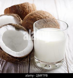 Trinken ein Glas Milch oder Joghurt auf blau serviette auf weiße Holztisch mit Kokosnuss beiseite Stockfoto