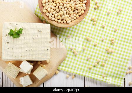 Flach auf Soja Tofu Tofu auf Schneidebrett mit Schüssel Bohnen beiseite. Pflanzliche alternative Ersatz für Käse Stockfoto