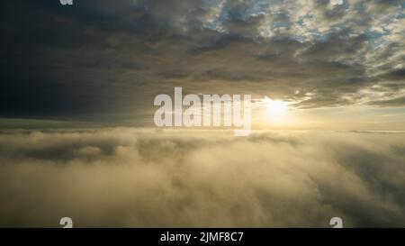 Luftaufnahme. Fliegen Sie im Nebel über den frühen Morgenwolken in der aufgehenden Sonne. Luftkamera aufgenommen. Flug über dem Kl Stockfoto