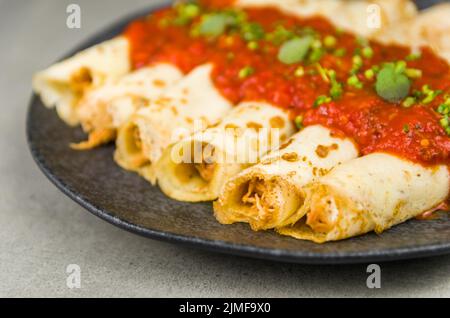 Brasilianische Pfannkuchen mit Huhn, Tomatenbolognese-Sauce, gerollte Pfannkuchen. Stockfoto