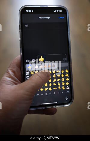 Das iPhone 13 pro max wird mit einer kaukasischen Hand gehalten, die einen Vater antwortet, Daumen nach oben Emoji Stockfoto