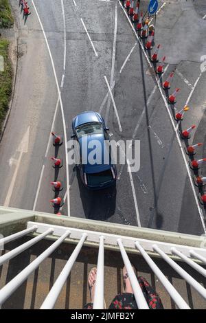 Blick von einer Fußgängerbrücke auf die Straße A259, die erweitert wird und mit Verkehrskegeln versehen ist, die Bereiche markieren. Stockfoto