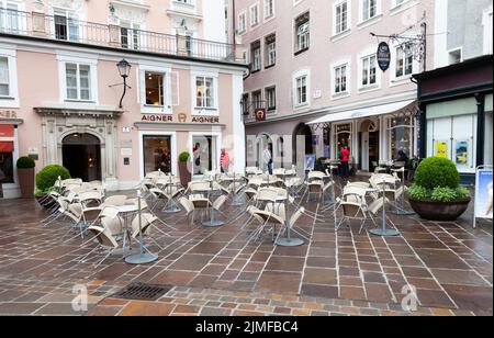 Weiße Plastikstühle stehen vor der offenen Zeit in Salzberg, Österreich, in einem Food Street Shop am Tisch. Stockfoto