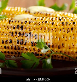 Gegrillter Mais Maiskolben mit Butter schmelzen und Grüns auf Ton Teller Stockfoto