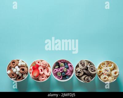 Gerolltes Eis in Kegelbecher auf blauem Hintergrund Stockfoto