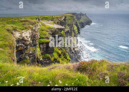 Eine Gruppe von Menschen, die die berühmten Cliffs of Moher, Irland, besichtigen Stockfoto