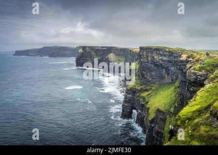 Eine Gruppe von Menschen, die die berühmten Cliffs of Moher, Irland, besichtigen Stockfoto