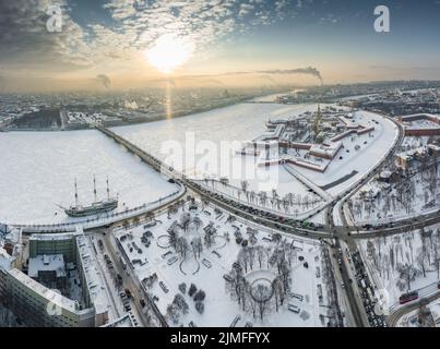 Drohne Sicht des Winters St. Petersburg bei Sonnenuntergang, gefrorener Neva Fluss, Dampf über der Stadt, Peter und Paul Festung, Autoverkehr Stockfoto
