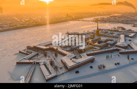 Drohne Sicht des Winters St. Petersburg bei Sonnenuntergang, gefrorener Neva Fluss, Dampf über der Stadt, Peter und Paul Festung, Autoverkehr Stockfoto