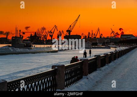 Der Bau von nuklearen Eisbrechern bei magischem Sonnenuntergang, Kräne der baltischen Werft in einem frostigen Wintertag, Dampf über die Stockfoto