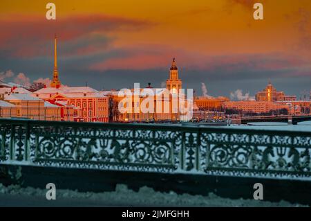 Winterpanorama von St. Petersburg bei Sonnenuntergang, goldener Turm von Peter und Paul Festung, Kunstkamera Turm, Böschung mit b Stockfoto