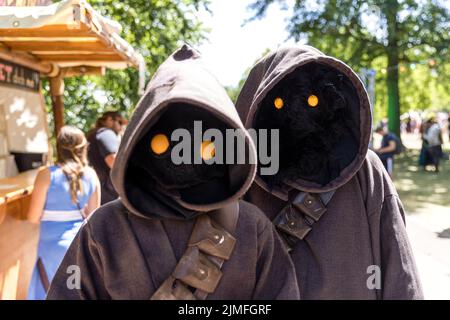 Cottbus, Deutschland. 05. August 2022. Besucher des Elbenwalder Festes, gekleidet als Jawas aus der Star Wars-Serie, wandern durch den Spreeauenpark. Das Elbenwald Festival ist ein dreitägiger Treffpunkt für alle Altersgruppen, die Filme, Fantasy, Spiele, Konzerte und jede Kombination von allen genießen. Quelle: Frank Hammerschmidt/dpa/Alamy Live News Stockfoto