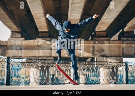 Skateboarder macht einen Trick auf der Straße städtischen Hintergrund Stockfoto