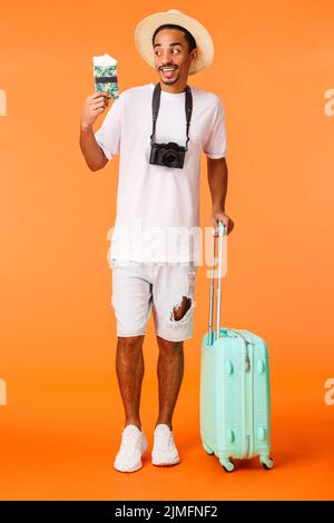 In voller Länge vertikale Aufnahme aufgeregt glücklich afroamerikanischen männlichen Reisenden, kann nicht warten Schluck Cocktail unter der Sonne und genießen genial V Stockfoto