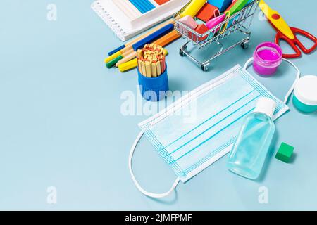 Schulbedarf, poppit Anti-Stress, Gesichtsmaske, Flasche Desinfektionsmittel, für den Rückweg in die Schule auf blauem Hintergrund. Covid-19 Vorsichtsmaßnahmen, gesund zu bleiben. C Stockfoto