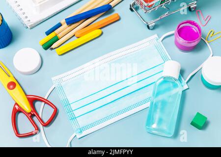 Schulbedarf, poppit Anti-Stress, Gesichtsmaske, Flasche Desinfektionsmittel, für den Rückweg in die Schule auf blauem Hintergrund. Covid-19 Vorsichtsmaßnahmen, gesund zu bleiben. Stockfoto