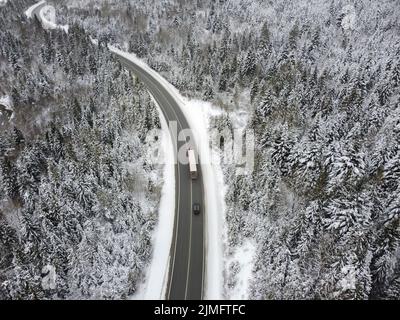 Kurvige Straße durch den Wald im Winter. Asphalt durch den Pass auf die Spitze des Berges in Rumänien. Stockfoto