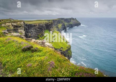 Eine Gruppe von Menschen, die die berühmten Cliffs of Moher, Irland, besichtigen Stockfoto