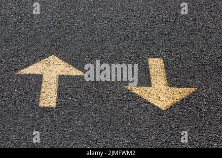 Gelbe Pfeile auf der Asphaltstraße, hin und her. Stockfoto