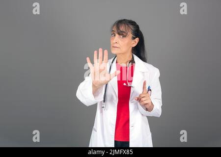 Hübsche Frau, die ernst, streng, unzufrieden und wütend aussieht und eine offene Handfläche zeigt, die eine Stoppgeste macht Stockfoto