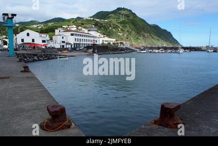 Die Hafenpromenade und der Yachthafen der Stadt, rostige Anlegestellen an der Betonanlegestelle im Vordergrund, Povoacao, Sao Miguel Island, Azoren, Portugal Stockfoto