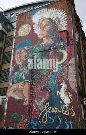 Brunswick Street, Glasgow, Schottland, Großbritannien. Wandbild am Giebel des Gebäudes mit dem Titel Fearless. Das neue Wandgemälde wurde anlässlich der Konferenz COP26 in der Merchant City veröffentlicht. Fearless Collective hat das Design enthüllt, das die Gesichter der indigenen Gemeinschaft zeigt, die während der Konferenz eine kontinuierliche und unverblühte Präsenz gezeigt haben. Das Kunstwerk auf der Brunswick Street entstand aus einem Workshop in Zusammenarbeit mit der brasilianischen indigenen Volksartikulation (APIB) und anderen indigenen Führern, die COP26 Jahre alt sind, um ihre Nationen zu repräsentieren. Stockfoto