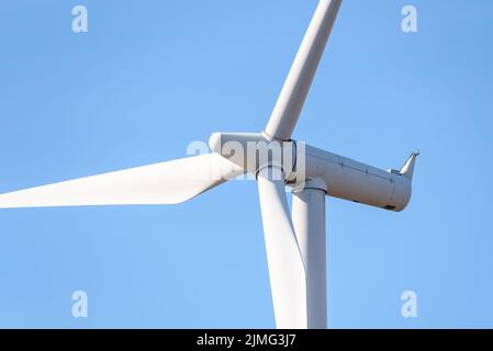 Nahaufnahme einer Windkraftanlage, die im Herbst Strom gegen den blauen Himmel erzeugt Stockfoto