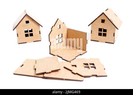 Teilweise zusammengebaute Spielzeughäuser mit auf weißem Hintergrund verstreuten Bausatzteilen. Kreatives Blockentwicklungskonzept. Stockfoto